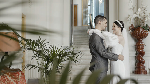 A girl in a beautiful snow- white dress with a bouquet in her hands and a grrom in official suit. Action. A wonderful touching moment of wedding.