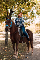 Obraz premium A woman sits on top of a horse. Horse riding in the autumn park