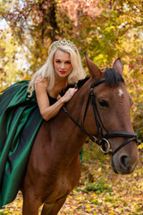 Fototapeta premium A woman in a long dress sits on a horse. Autumn forest, horse breeding
