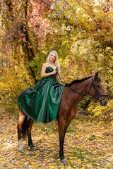 A woman in a long dress sits on a horse. Autumn forest, horse breeding
