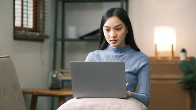 Asian charming person sit hold netbook browsing have good mood working home indoors.