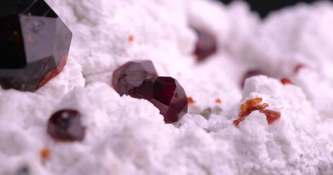 Spessartine garnet on orthoclase matrix  with rotating light 4k. macro detail texture background. close-up raw rough unpolished semi-precious gemstone

