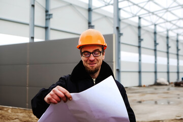 construction site engineer worker. portrait of smiling man in a hardhat and glasses at a construction site. Construction of a new building. Man looking at drawing