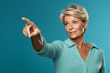 A photo of a middle aged woman pointing at empty space on a teal background, black firday image