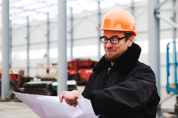 construction site engineer worker. portrait of smiling man in a hardhat and glasses at a construction site. Construction of a new building. Man looking at drawing