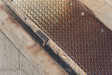 industrial background, featuring textured concrete pavement and rusty metal plate with anti-slip...