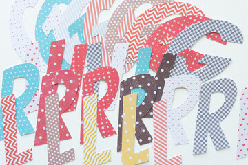 machine-cut decorative letters layered or overlapping on blank paper (combined they form the word "girl")