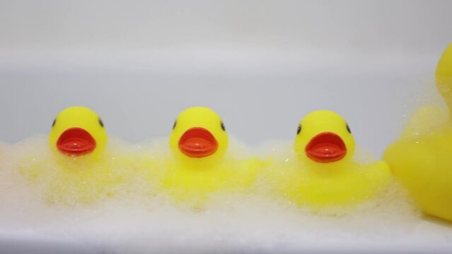 Yellow rubber ducks with soap bubble bath, light background with bubbles. Kids spa concept. Children`s bath time concept