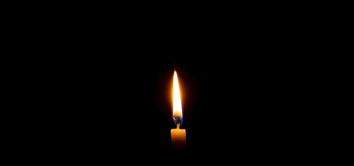 Single burning candle flame or light glowing on a small yellow candle on black or dark background...
