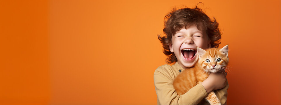 A smiling little boy with his cat, copy space orange background