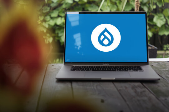 Drupal logo, a free and open-source web content management system (CMS) written in PHP, displayed on a MacBook Pro screen