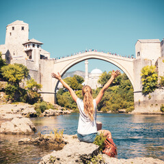 Happy woman traveler in Mostar city- Old bridge and river- tour tourism,travel,vacation destination