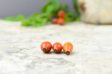 rosehip fruits, composition with green leaves, light background