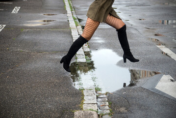 Closeup of sexy woman jumping on puddle in the street - 654907008