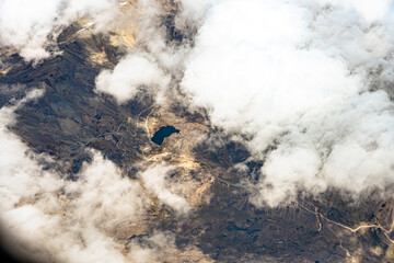 View from 10,000 meters (33,000 feet) of the mountains and arid landscape of western Peru. Dry river paths, dense clouds and no vegetation. - obrazy, fototapety, plakaty