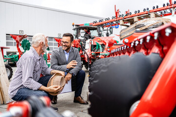 Farmer and tractor dealer discussing about harrow and farming equipment.