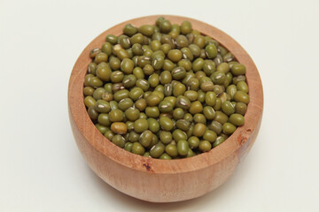 Mung beans or Vigna radiata or green gram, in a wooden bowl, isolated on white background