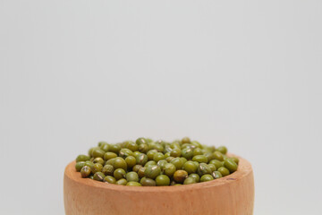 Mung beans or Vigna radiata or green gram, in a wooden bowl, isolated on white background