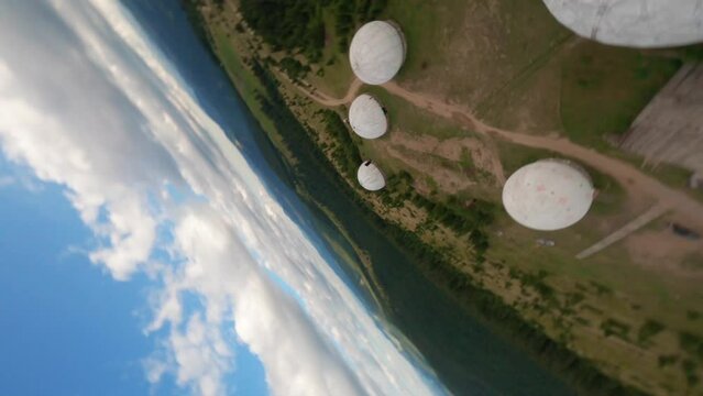 FPV, Abandoned radar station Pamir in Carpathian mountains, research station on top of the mountain in the Carpathians in Ukraine. large white balloons designs in the mountains among the fir trees