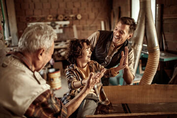Multigenerational family of male carpenters teaching their youngest one the ways in a carpentry shop