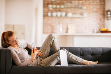 Young woman using her smartphone on the couch at home