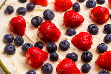 Fresh juicy strawberries and blueberries blueberries in thick whipped cream close-up