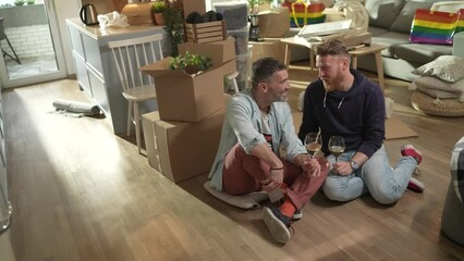 Young male gay couple having wine and taking selfies in their new apartment after moving in - Powered by Adobe