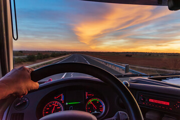 View from inside a truck of an empty highway under a dramatic sky.