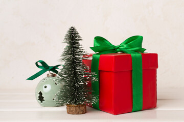 Red gift box with green ribbon and bow on table
