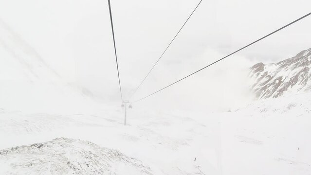 Timelapse of White red closed ski lift cabins in fast motion on cable rope with skiers in snowy day. Ski resort reopens. Georgia winter holidays in Gudauri. Kobi slopes freeride