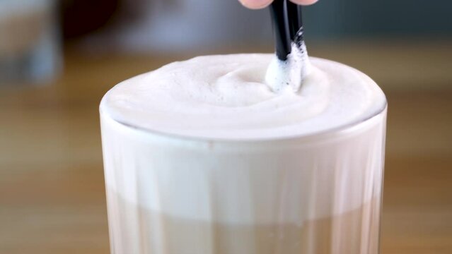 Frappe with sugar syrup coffee with milk delicious drink high foam stir with a straw in a restaurant Glass of a iced coffee with cream milk. Cold brew coffee drink with ice. Early morning sun light. 