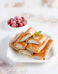 Crepes with cottage cheese, strawberry and mint. Thin pancakes with fillings