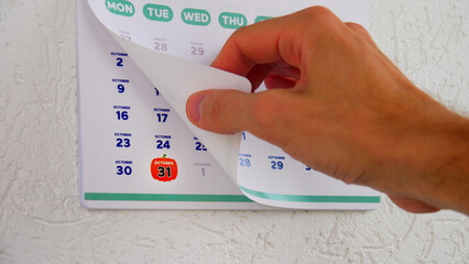 Close-up of a male hand flipping through the page of 2023 wall calendar followed by the next one...