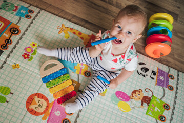 Toddler playing with toys on the colourful mat. Baby playing with a wooden xylophone.