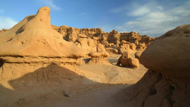 Low drone in slow motion flying past Goblin Valley Hoodoos sandstone rocks during sunset. Utah