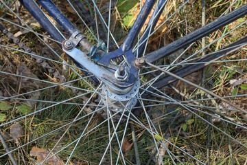 part of a bicycle wheel with gray spokes, a hub and a brake on a blue bicycle frame lies on the...
