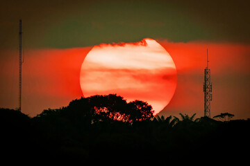 Huge sun at sunset urban silhouette with antennas