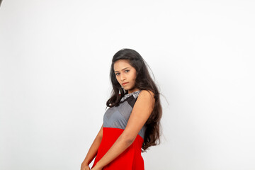 Studio shot of a young, beautiful Indian female model in casual wear wearing red and grey designer top and black jeans against white background. Female model. Fashion Portrait.