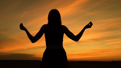 Calm woman meditating at sunset dark silhouette spiritual practice outdoors