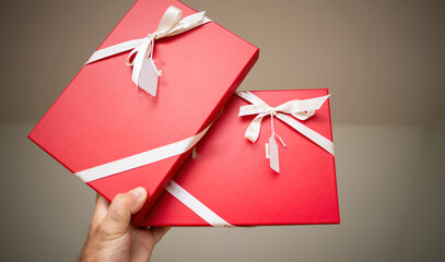 A masculine hand grasps a two red striking, crimson gifts, meticulously enveloped in the soft...