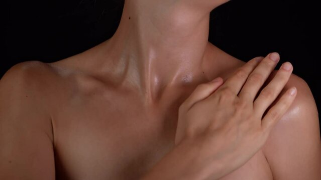 Closeup studio shot of body part, woman applying body lotion on her shoulder and chest area smooth skin.