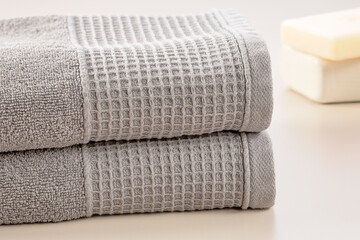 Bathroom accessories. Stack of gray soft towels and bar of soap on a gray background