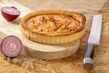 French onion pie with bacon on a kitchen board
