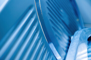 Extreme close-up of the blade on a professional kitchen slicer, highlighting its sharpness and precision