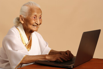 An elderly woman sitting at a table using a laptop computer. This image can be used to depict technology usage by seniors or the concept of lifelong learning.