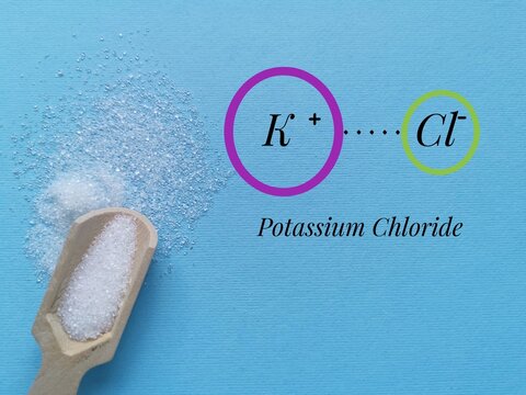 Structural chemical formula of potassium chloride with white potassium salt crystals. Potassium chloride is a mineral supplement that is used to prevent or treat low levels of potassium in the blood.
