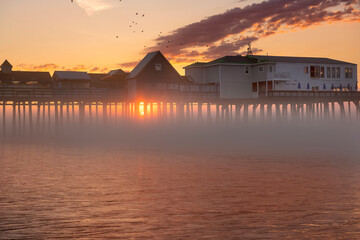 Obraz premium old wooden pier on the ocean at dawn in the fog. USA. Maine. Portland. Old Orchard Beach.