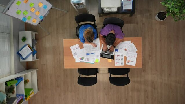 Top view of office boardroom with young male and female workers. Team members working with documents, coworker bring them coffee.