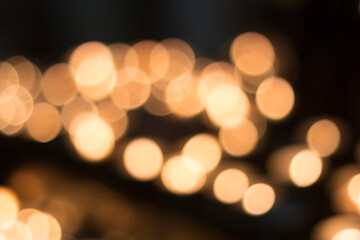 blurred warm light circles, boquet from small prayer candles inside a chrisitan church