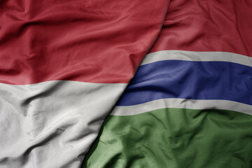big waving realistic national colorful flag of indonesia and national flag of gambia .